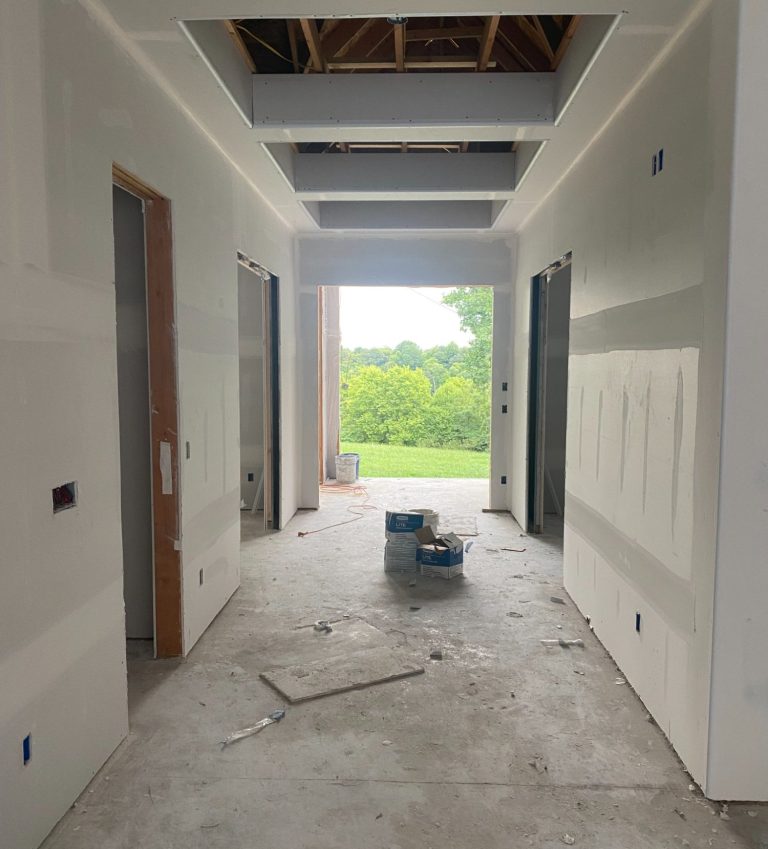 Fayetteville New Build Interior hallway under construction with unfinished walls and a view of greenery outside.